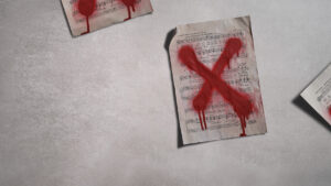 A sheet of music lies on a grey surface with a large, red, spray-painted X across it. Other music sheets marked with red paint are partially visible in the corners.